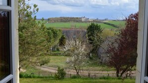 A view from a window overlooking a rural landscape with fields, trees, and a distant building. - Charming house with private garden, fireplace and WIFI (Seuilly)