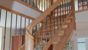 A wooden staircase with metal railings, leading to a landing with a door and a window. - Charming house with private garden, fireplace and WIFI (Seuilly)