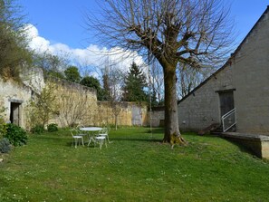 A courtyard with a stone building, a tree, and a table with chairs. - Charming house with private garden, fireplace and WIFI (Seuilly)