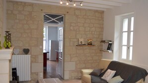 A living room with a stone wall, a sofa, a coffee table, and a fireplace. - Charming house with private garden, fireplace and WIFI (Seuilly)