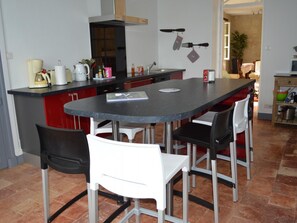 A compact kitchen with a central island, white chairs, and a red cabinet. - Charming house with private garden, fireplace and WIFI (Seuilly)