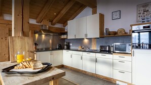 Una cocina moderna con armarios blancos, encimera de madera y campana extractora de acero inoxidable.