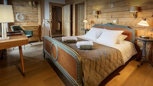 Un dormitorio con piso de madera, una cama con cabecera, una mesita de noche y una silla.
