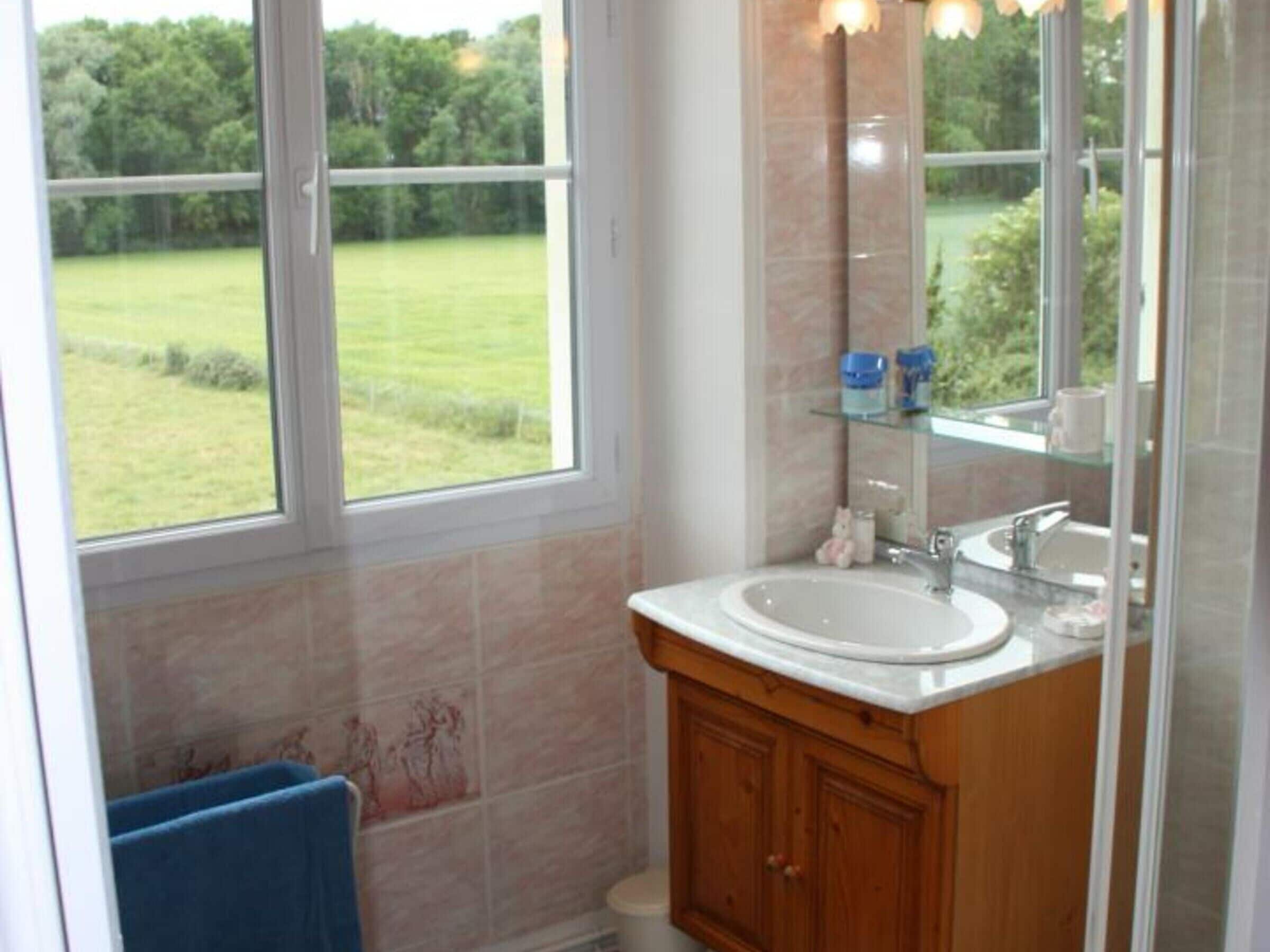Une salle de bain avec une grande fenêtre, un lavabo et un miroir.