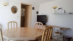 A dining area with a wooden table and chairs, a television, and a shelf with items. - Mökki Reisch - La Cadiere D'azur (La Cadière-d'Azur)