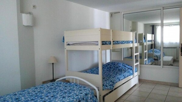 A room with two bunk beds, a mirror, a lamp, and a window.