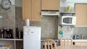 A compact kitchen with a refrigerator, microwave, and wooden cabinets. - Mökki Reisch - La Cadiere D'azur (La Cadière-d'Azur)