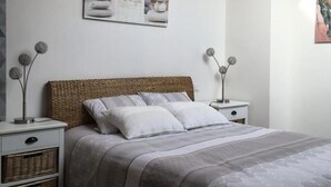 Quarto com cama, mesas de cabeceira e objetos decorativos.