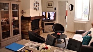 Una sala de estar con chimenea, televisor y comedor con mesa y sillas.
