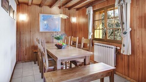 A wooden dining room with a large table, chairs, a bench, a map on the wall, and a window with curtains. - Chalet Chenavray - Manigod base for 10, spa & great skiing - OVO Network (Manigod)