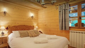 A cozy wooden room with a bed, two bedside lamps, a radiator, and a window with curtains. - Chalet Chenavray - Manigod base for 10, spa & great skiing - OVO Network (Manigod)