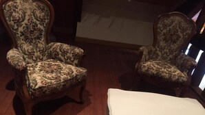 A room with two ornate armchairs with floral upholstery and a white bench.