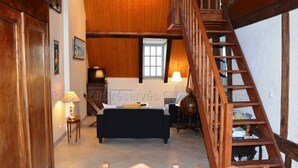 Un amplio salón con una escalera de madera, un sofá, una mesa y una lámpara.