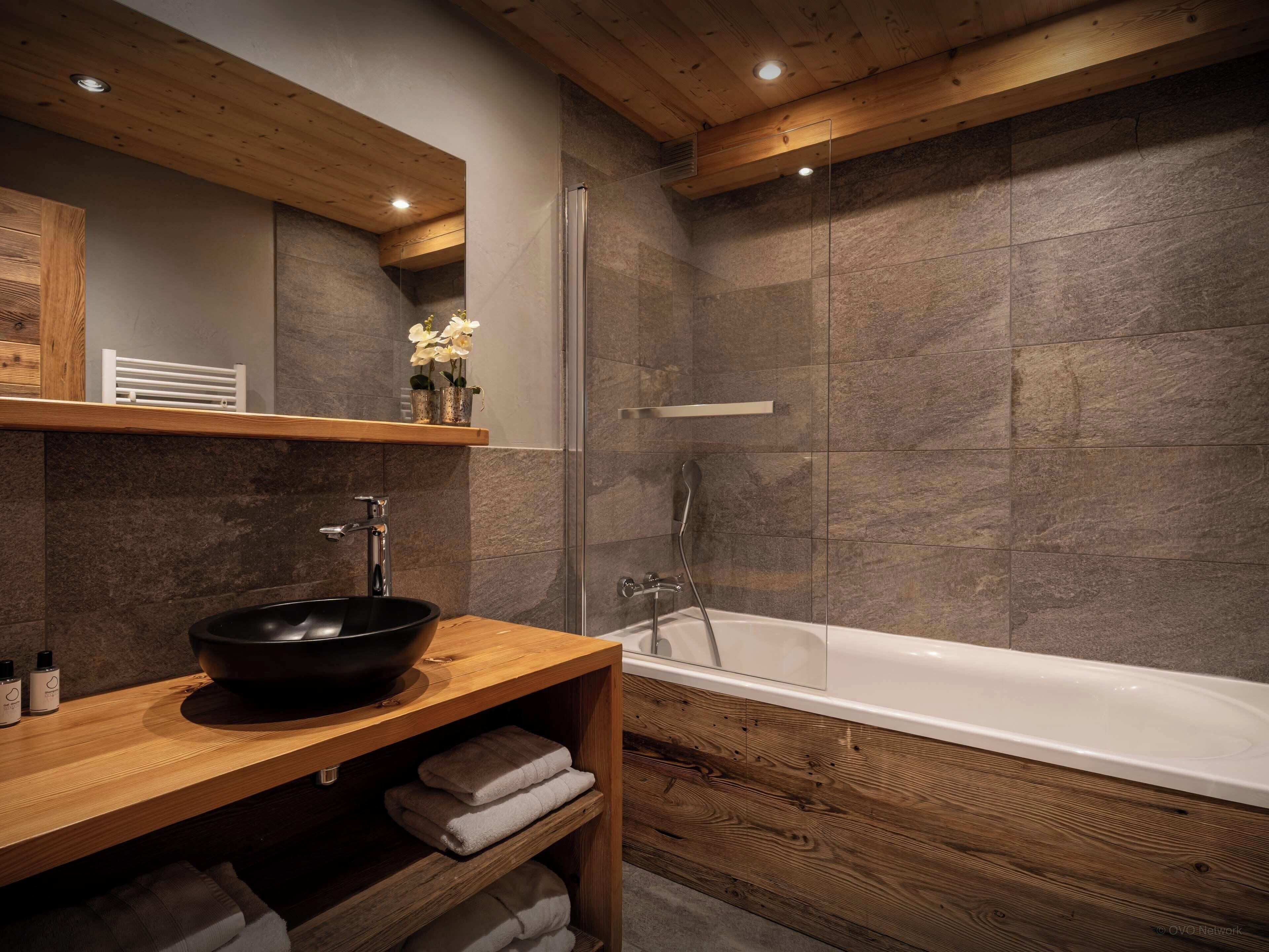 Une salle de bain moderne avec un meuble-lavabo en bois, une baignoire et un espace douche.
