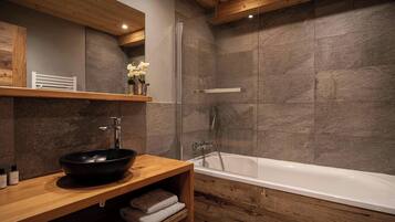 Une salle de bain moderne avec un meuble-lavabo en bois, une baignoire et un espace douche.