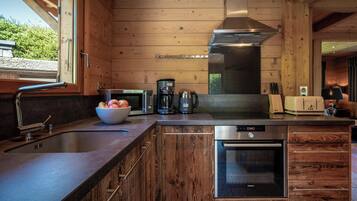A modern kitchen with wooden paneling, stainless steel appliances, and a large window.