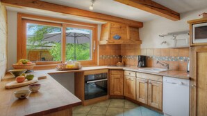 Una cocina con armarios de madera, horno empotrado y una ventana con paraguas.
