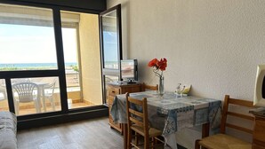 Ein Essbereich mit Tisch, Stühlen, einem Fernseher und Meerblick.