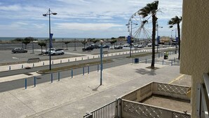 Eine Küstenstraße mit Parkplatz, Fußgängerweg und einem Riesenrad im Hintergrund.