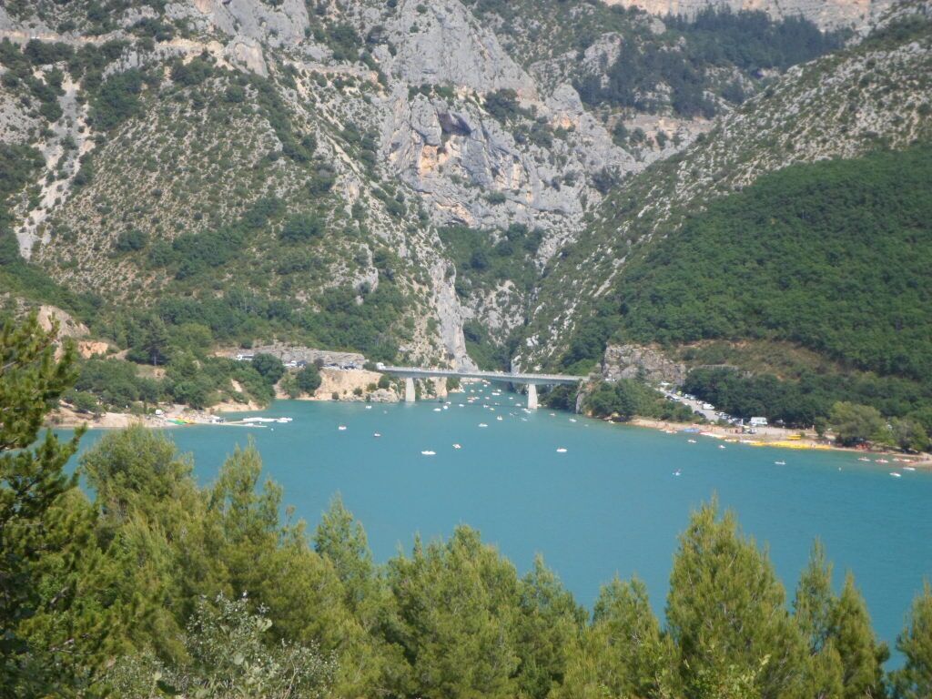 A mountainous landscape with a bridge over a body of water, surrounded by greenery.