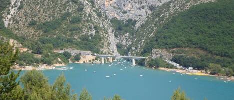 A mountainous landscape with a bridge over a body of water, surrounded by greenery.