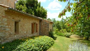 Un bâtiment en pierre avec un petit jardin devant, où l’on peut admirer une variété de plantes et un ciel dégagé.