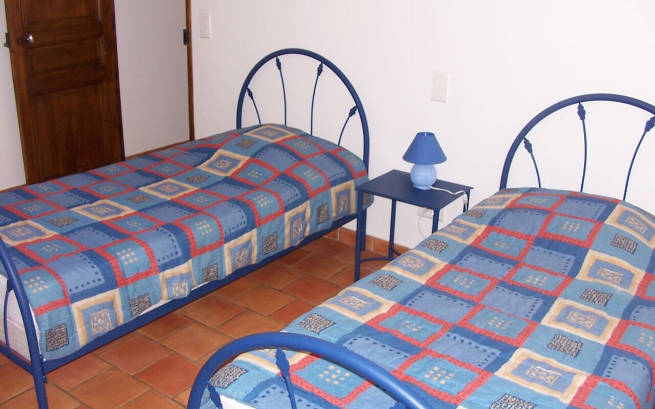Una camera da letto con due letti in metallo, una porta in legno e un piccolo tavolo con una lampada.