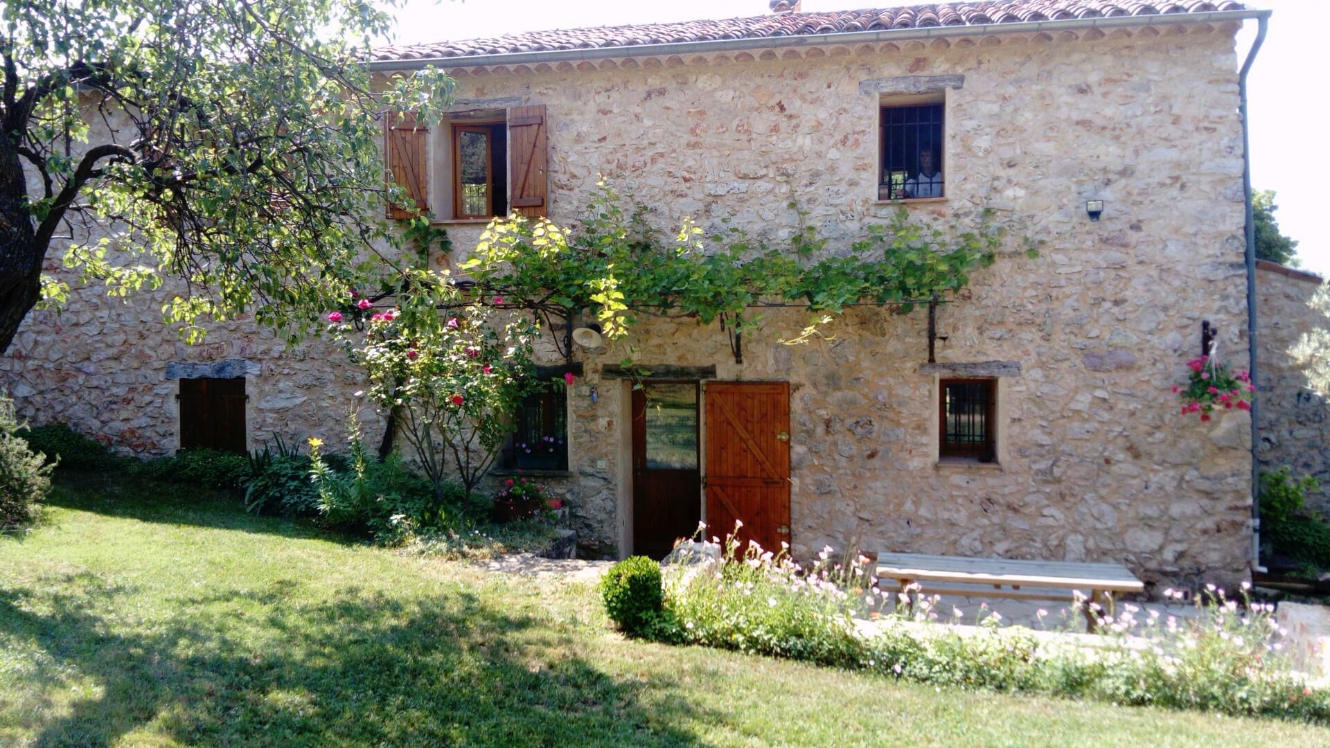 A stone building with a wooden door, windows, and a small garden area.