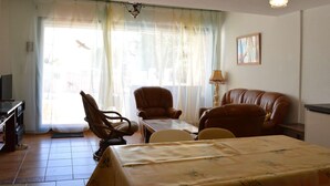 A room with a bed, two chairs, a small table, a lamp, and a television. - Cozy 4BR House, 750m from Beach, Sleeps 8, Pet-Friendly, Terrace, Parking, WiFi Optional (Fleury-Saint-Pierre-la-Mer)