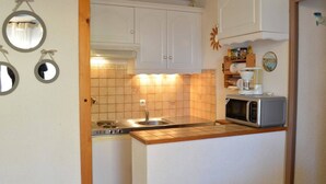 A compact kitchen with white cabinets, a stove, a sink, and a microwave. - Saint Pierre la Mer, 2-room appt, cabin, sleeps 6, near beach, pets allowed (Fleury-Saint-Pierre-la-Mer)