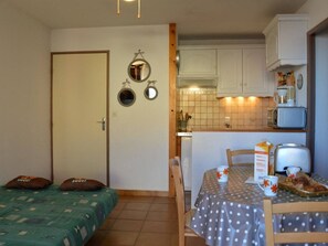 A small, compact room with a bed, a table with breakfast items, a microwave, and a sink in the kitchenette.