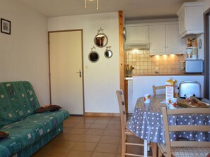 A compact living space with a kitchenette, a dining area, and a sofa.