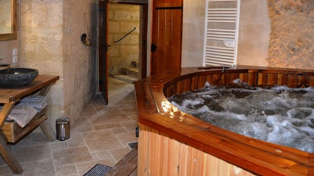 Un baño rústico con una bañera de madera, un lavabo de piedra y una zona de ducha.