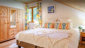 A bedroom with a large bed, wooden wardrobe, and a window with curtains. - Les Roses des Alpes - luxury mountain break, views & spa - OVO Network (Thônes)