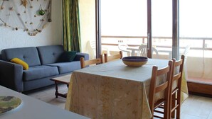 En stue med sofa, et bord med skål og en balkon med stole.