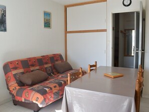 A room with a sofa and a table, a door, and a wall with a clock and a picture.