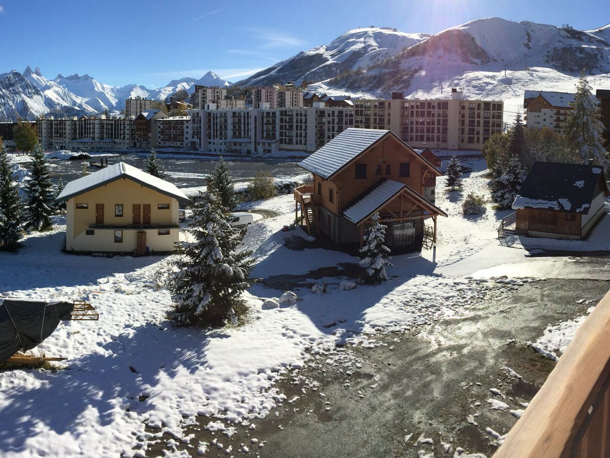 Ein verschneites Dorf mit traditionellen Holzhäusern und einem modernen Hotelkomplex im Hintergrund.