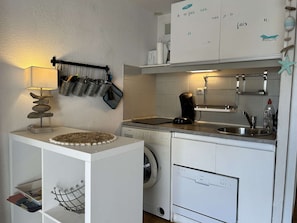 A compact kitchen with a washing machine, a coffee maker, and a small countertop.