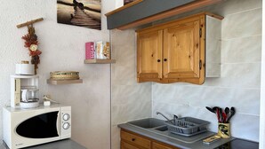 A compact kitchen with a microwave, a coffee maker, wooden cabinets, and a sink. - Cozy 4-Sleeper with A/C, Terraces & Direct Marina Access (Port Camargue)