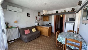 A compact living space with a kitchenette, a dining area, and a sofa. - Cozy 4-Sleeper with A/C, Terraces & Direct Marina Access (Port Camargue)