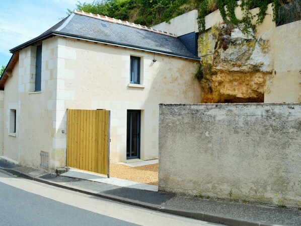 A two-story house with a wooden gate, a concrete wall, and a sloped roof. - Unique cottage with garage and private courtyard in Touraine (Savonnières)