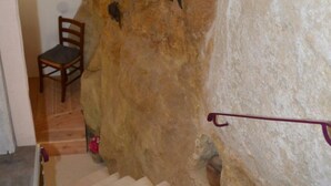 Una escalera con una pared texturizada, una silla de madera y un pequeño adorno en la parte inferior.