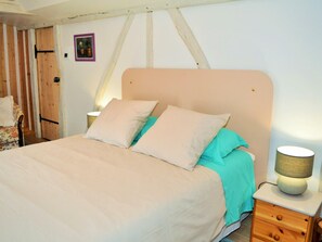 A bedroom with a bed, pillows, a nightstand, a lamp, and a wooden door. - Unique cottage with garage and private courtyard in Touraine (Savonnières)