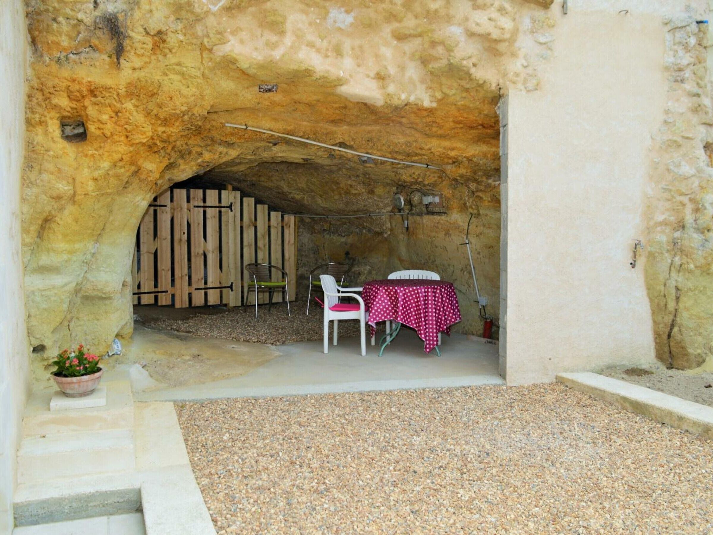 Un espace extérieur aménagé avec une table et des chaises, situé sous un surplomb rocheux.