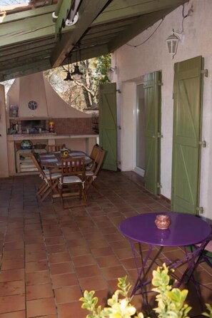 Relax in this charming outdoor space with a brick floor, wooden table, and comfortable seating.