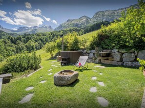 A backyard with a stone fire pit, a wooden deck, and a chair.