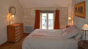 Un dormitori amb llit, aparador i finestra amb cortines.