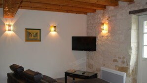 Un saló amb un sofà de cuir, una taula de centre i un televisor de pantalla plana fixat a una paret de pedra.
