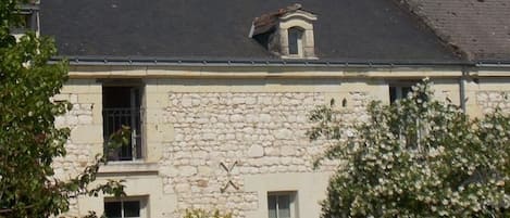 A stone building with a tiled roof, a small dormer window, and a visible door.