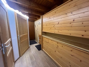 Een houten interieur met een deur, een kleine gang en een wand met een plank.